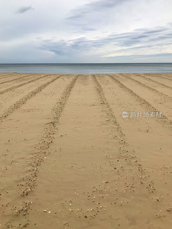 由拖拉机/犁压实的金色海滩沙子的图像，卵石轨道模式后留下的沙子犁地，海滩假日度假壁纸背景图像海报，文本复制空间